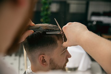 Image showing Close up master barber, stylist does the hairstyle to guy, young man. Professional occupation, male beauty concept