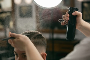 Image showing Close up of client of master barber, stylist during getting care of hairstyle. Professional occupation, male beauty concept