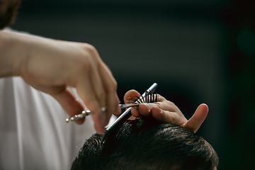 Image showing Close up hands of master barber, stylist does the hairstyle to guy, young man. Professional occupation, male beauty concept