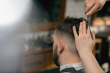 Image showing Close up hands of master barber, stylist does the hairstyle to guy, young man. Professional occupation, male beauty concept