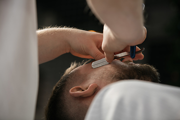 Image showing Close up hands of master barber, stylist does the hairstyle to guy, young man. Professional occupation, male beauty concept