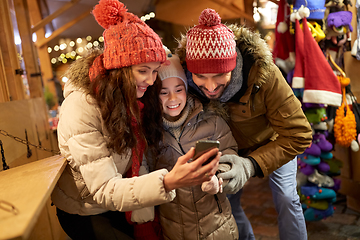 Image showing happy family with smartphone at christmas market