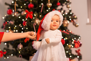 Image showing baby girl with mother over christmas tree at home