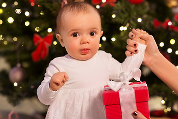 Image showing baby girl with gift over christmas tree at home