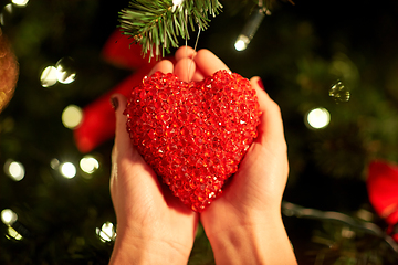 Image showing hands decorating christmas tree with red heart