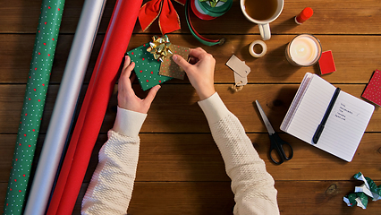 Image showing hands packing christmas gift and attaching tag