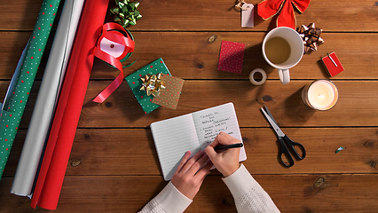 Image showing hands writing to do list in notebook on christmas