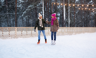 Image showing happy couple holding hands on skating rink