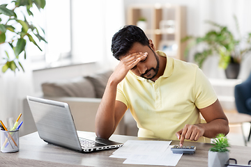 Image showing man with calculator and papers working at home