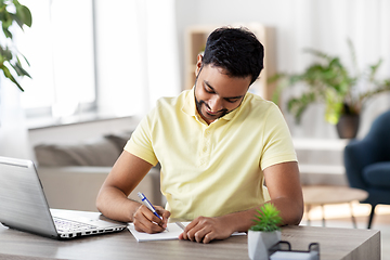 Image showing indian man with notebook and laptop at home office