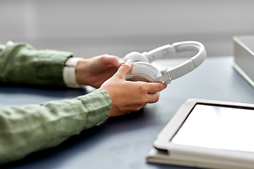 Image showing close up of hands with headphones at office