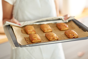 Image showing woman holding baking tray with pies at kitchen