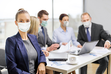 Image showing businesswoman in mask with colleagues at office