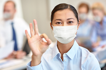Image showing businesswoman in mask showing ok sign at office
