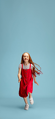 Image showing Happy redhair girl isolated on blue studio background. Looks happy, cheerful, sincere. Copyspace. Childhood, education, emotions concept