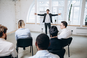 Image showing Male speaker giving presentation in hall at workshop. Audience or conference hall. Rear view of unrecognized participants.