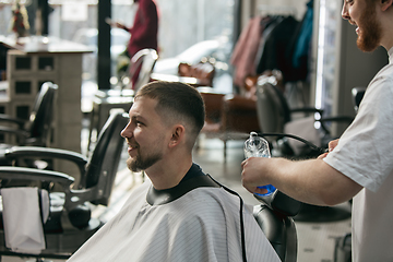 Image showing Master barber, stylist does the hairstyle to guy, young man. Professional occupation, male beauty concept