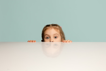 Image showing Happy kid, girl isolated on blue studio background. Looks happy, cheerful, sincere. Copyspace. Childhood, education, emotions concept