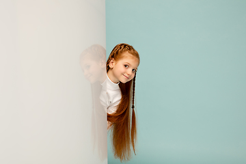 Image showing Happy kid, girl isolated on blue studio background. Looks happy, cheerful, sincere. Copyspace. Childhood, education, emotions concept