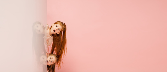 Image showing Happy kids, girls isolated on coral pink studio background. Look happy, cheerful, sincere. Copyspace. Childhood, education, emotions concept