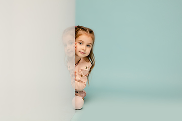 Image showing Happy kid, girl isolated on blue studio background. Looks happy, cheerful, sincere. Copyspace. Childhood, education, emotions concept