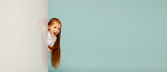 Image showing Happy kid, girl isolated on blue studio background. Looks happy, cheerful, sincere. Copyspace. Childhood, education, emotions concept