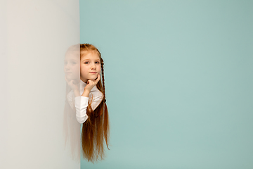 Image showing Happy kid, girl isolated on blue studio background. Looks happy, cheerful, sincere. Copyspace. Childhood, education, emotions concept