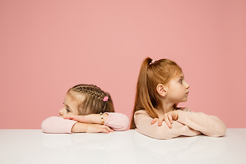 Image showing Happy kids, girls isolated on coral pink studio background. Look happy, cheerful, sincere. Copyspace. Childhood, education, emotions concept