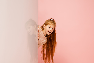 Image showing Happy kid, girl isolated on coral pink studio background. Looks happy, cheerful, sincere. Copyspace. Childhood, education, emotions concept