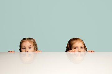 Image showing Happy kids, girls isolated on blue studio background. Look happy, cheerful, sincere. Copyspace. Childhood, education, emotions concept