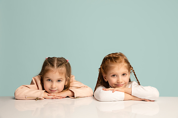 Image showing Happy kids, girls isolated on blue studio background. Look happy, cheerful, sincere. Copyspace. Childhood, education, emotions concept