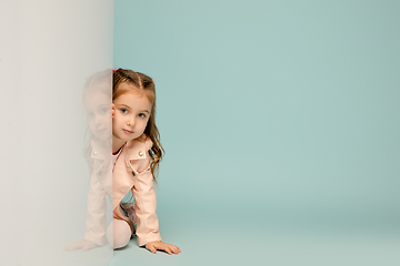 Image showing Happy kid, girl isolated on blue studio background. Looks happy, cheerful, sincere. Copyspace. Childhood, education, emotions concept