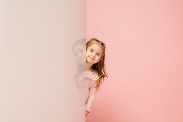 Image showing Happy kid, girl isolated on coral pink studio background. Looks happy, cheerful, sincere. Copyspace. Childhood, education, emotions concept
