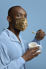 Image showing Portrait of medieval young man, grandee in vintage shirt and golden face mask on blue background.