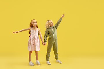 Image showing Childhood and dream about big and famous future. Boy and girl isolated on yellow studio background