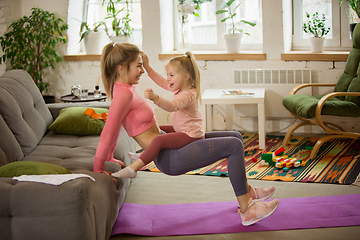 Image showing Young woman exercising fitness, aerobic, yoga at home, sporty lifestyle. Getting active with her child playing, home gym.