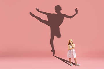 Image showing Childhood and dream about big and famous future. Conceptual image with girl and shadow of fit ballerina dancing on coral pink background