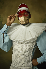 Image showing Portrait of medieval young man in vintage clothing and golden face mask on dark background.