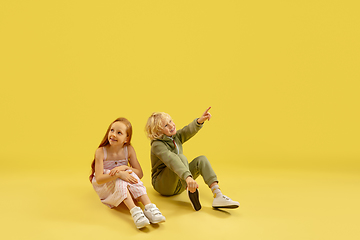 Image showing Childhood and dream about big and famous future. Boy and girl isolated on yellow studio background