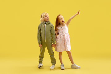 Image showing Childhood and dream about big and famous future. Boy and girl isolated on yellow studio background