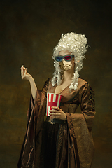 Image showing Portrait of medieval young woman in vintage clothes and golden face mask on dark background.