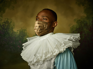 Image showing Portrait of medieval young man in vintage clothing and golden face mask on dark background.