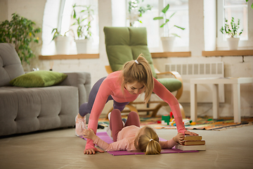 Image showing Young woman exercising fitness, aerobic, yoga at home, sporty lifestyle. Getting active with her child playing, home gym.