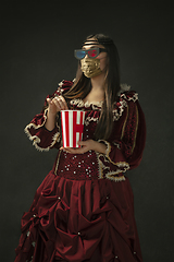 Image showing Portrait of medieval young woman in vintage clothes and golden face mask on dark background.