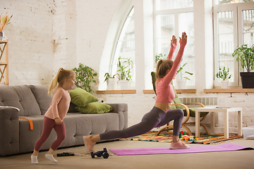 Image showing Young woman exercising fitness, aerobic, yoga at home, sporty lifestyle. Getting active with her child playing, home gym.