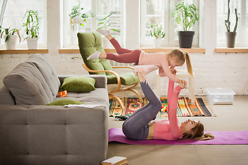 Image showing Young woman exercising fitness, aerobic, yoga at home, sporty lifestyle. Getting active with her child playing, home gym.