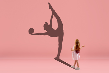 Image showing Childhood and dream about big and famous future. Conceptual image with girl and shadow of fit female rhythm gymnast on coral pink background
