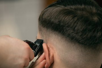 Image showing Close up of client of master barber, stylist during getting care of hairstyle. Professional occupation, male beauty concept