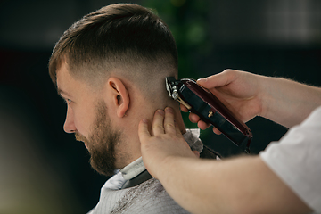 Image showing Close up master barber, stylist does the hairstyle to guy, young man. Professional occupation, male beauty concept