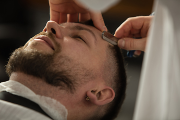 Image showing Close up hands of master barber, stylist does the hairstyle to guy, young man. Professional occupation, male beauty concept